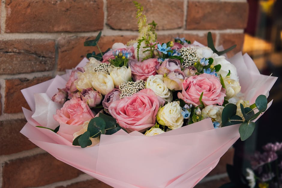 A floral bouquet featuring a mix of soft pink roses, creamy white eustoma, and delicate blue forget-me-nots, accented with white baby's breath and green eucalyptus leaves. The flowers are arranged in